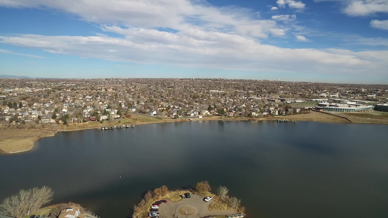 Aerial view of a broad lake with a residential shore and distant hills.