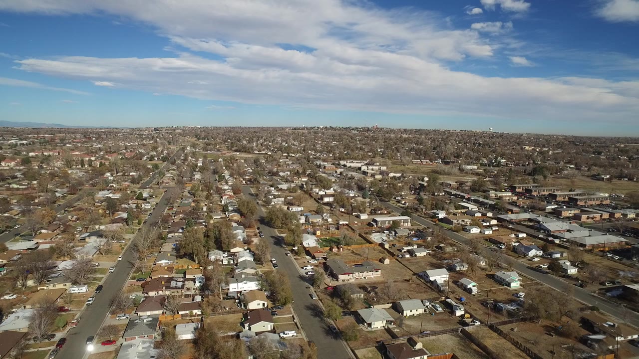 Aerial view over suburban houses and straight neighborhood streets.