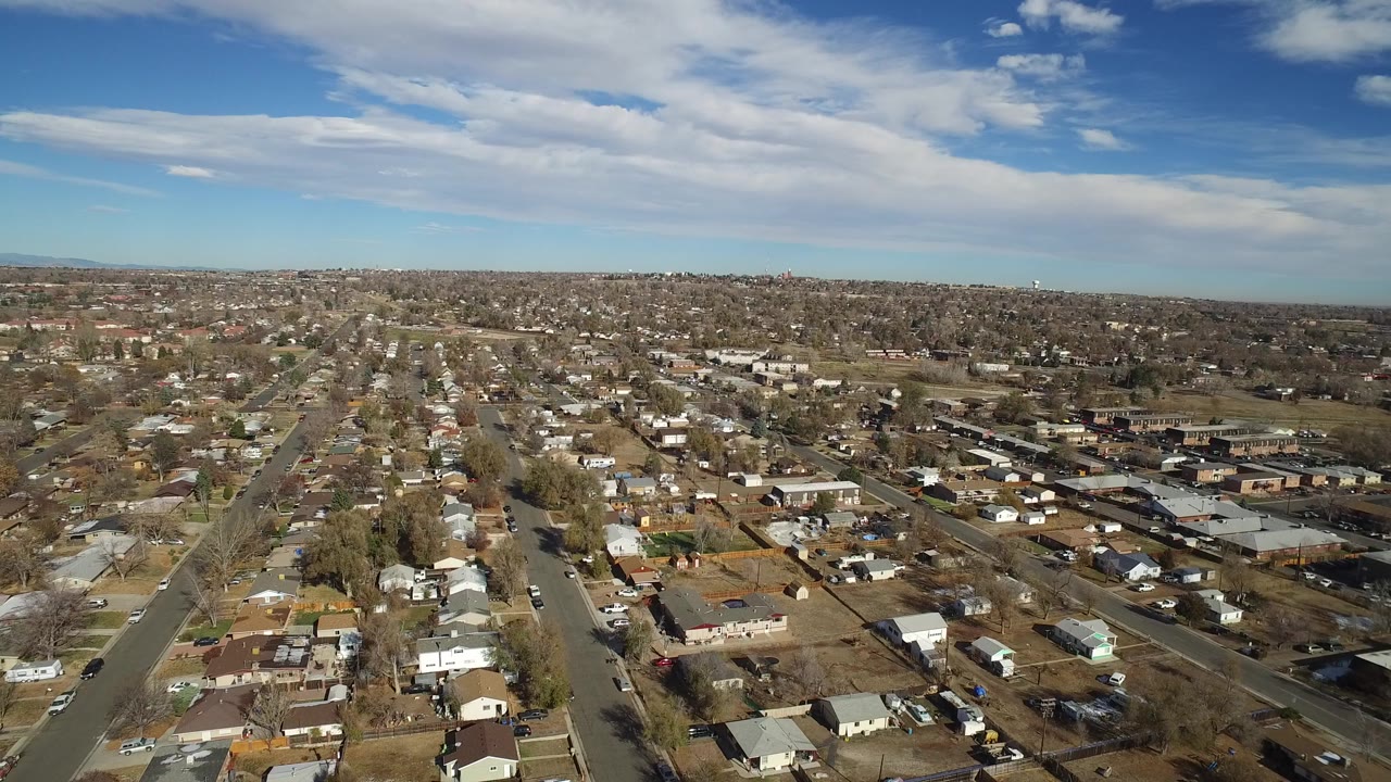 Aerial view of suburban streets and homes under a blue sky.