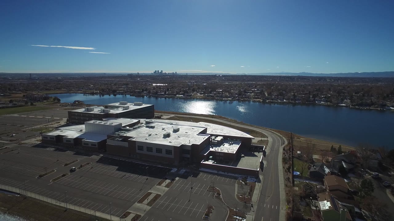 Drone-like aerial view of parking lots, buildings, and riverfront suburb.