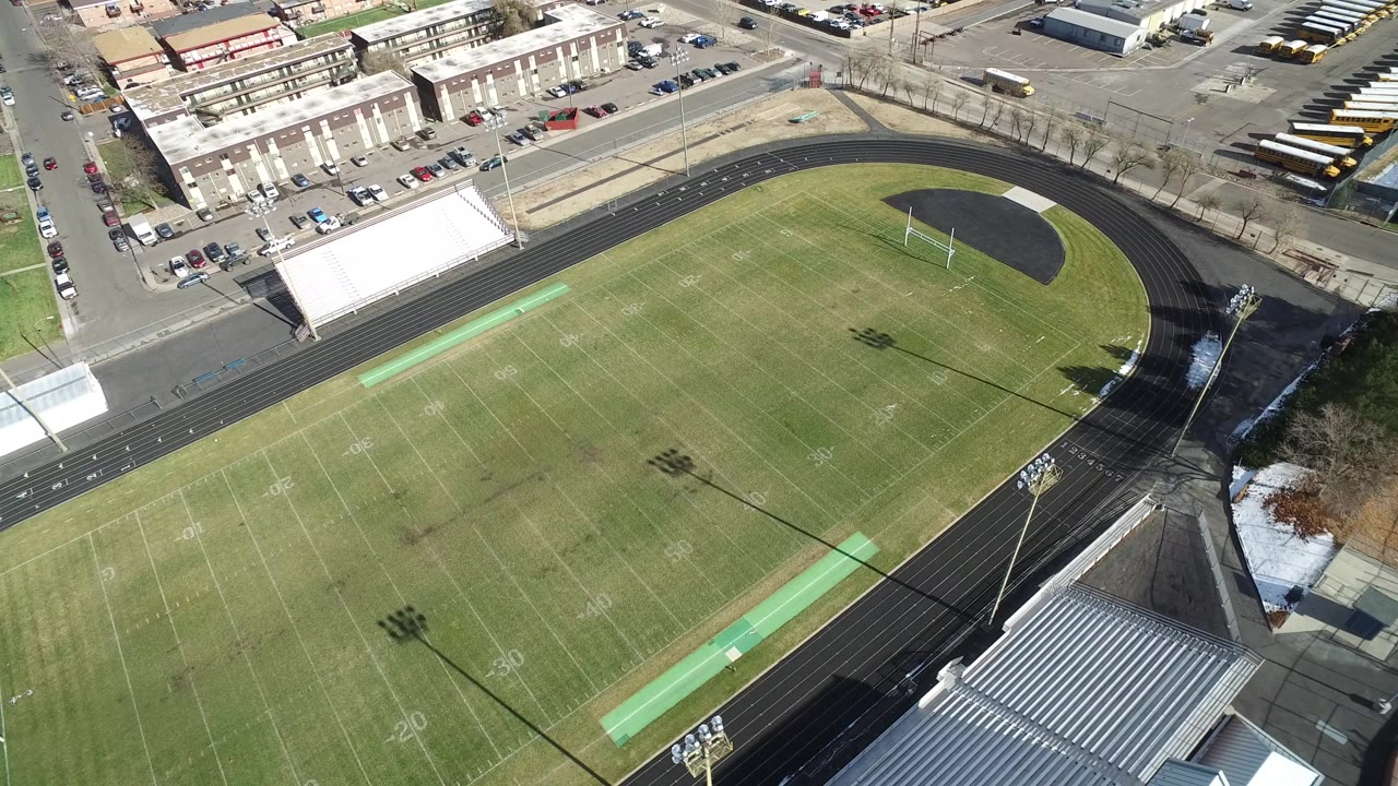 Aerial view of an empty football field and running track beside bleachers.