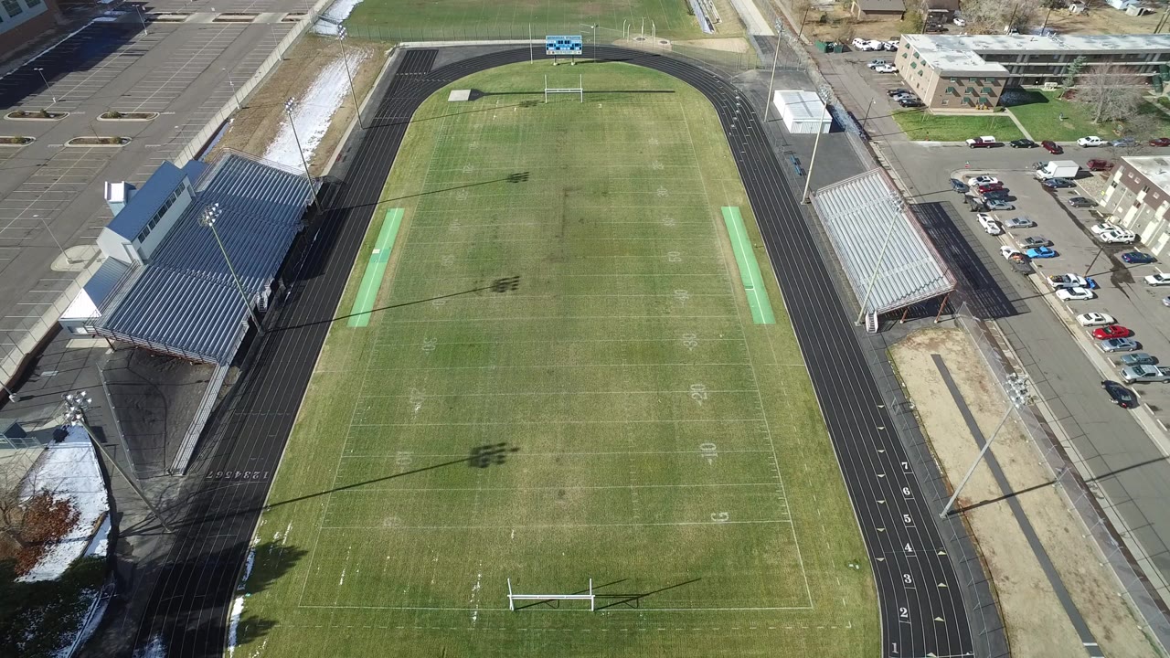 Overhead view of a football field and running track beside bleachers.