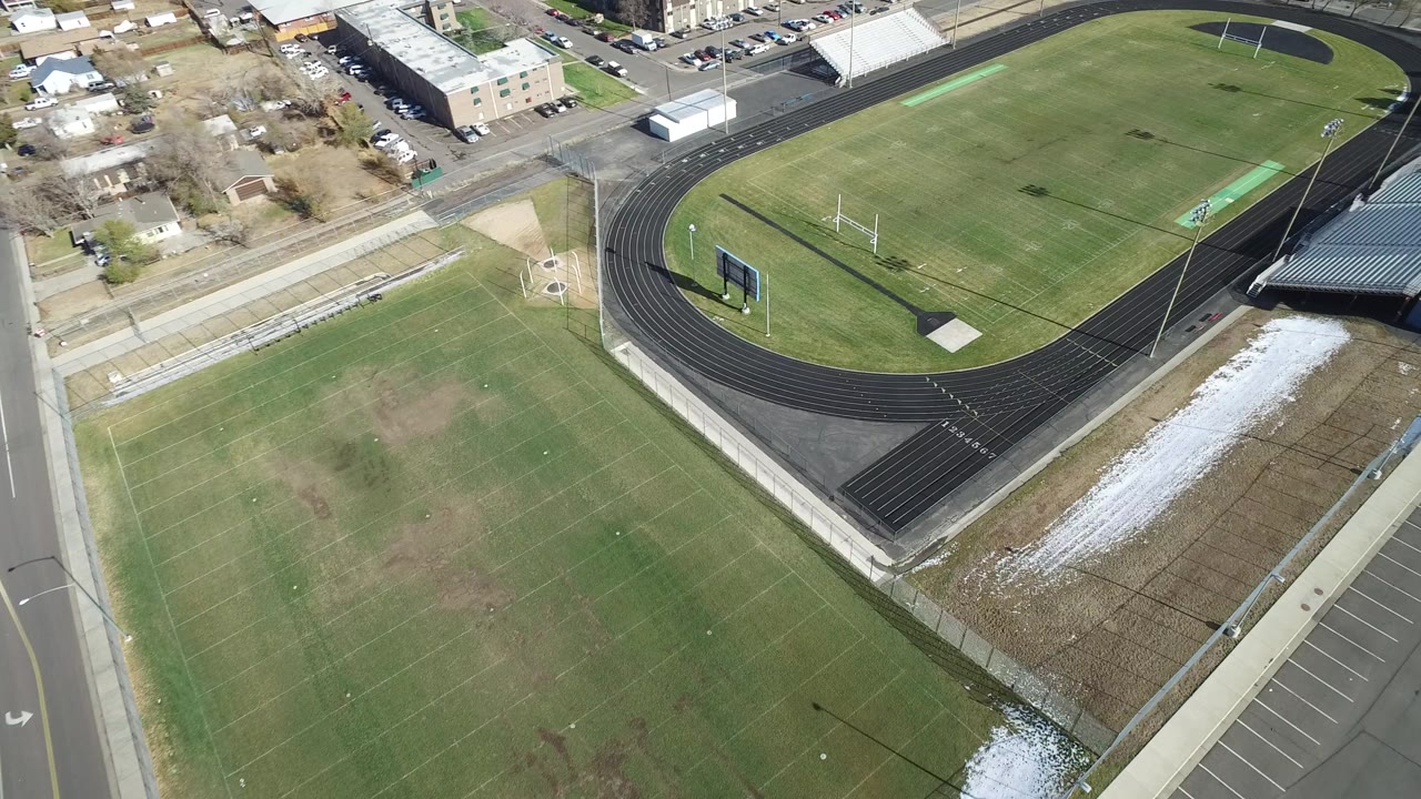 Aerial view of sports fields, running track, road, and parking lot.