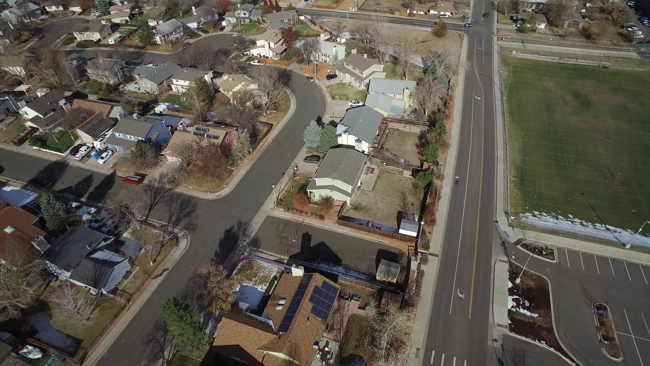 Aerial view of houses beside a road and green field.