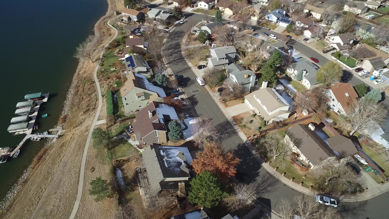 Aerial view of lakefront homes, a shoreline path, and covered docks.