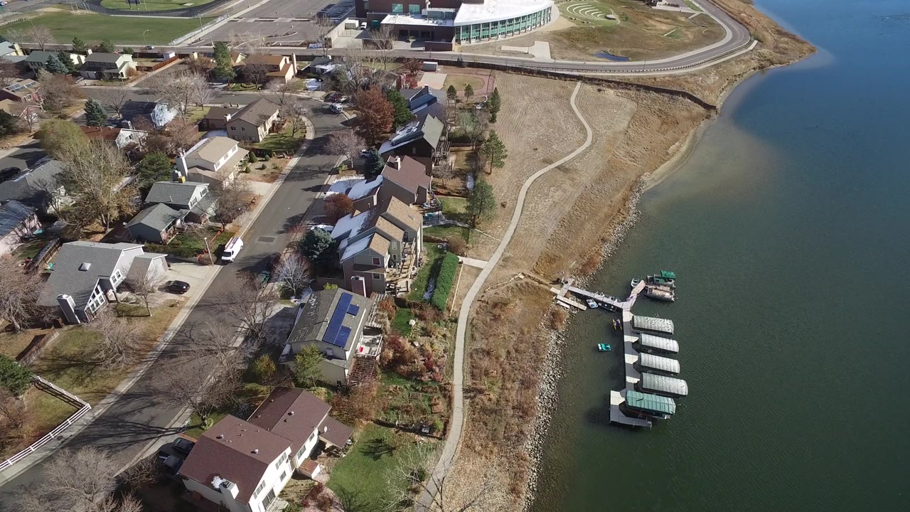 Lakeside subdivision from above with houses, a road, dry shoreline, and docks.