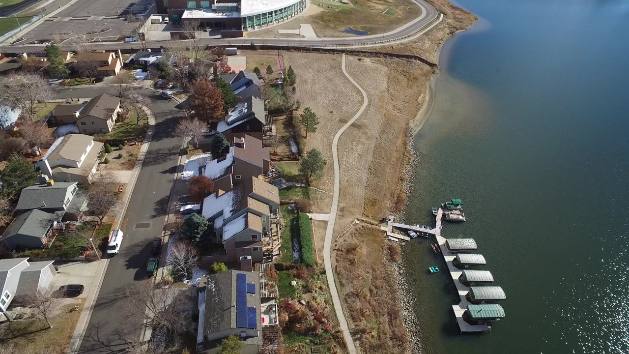 Aerial view of homes beside a lake with docks and a curving shoreline path.