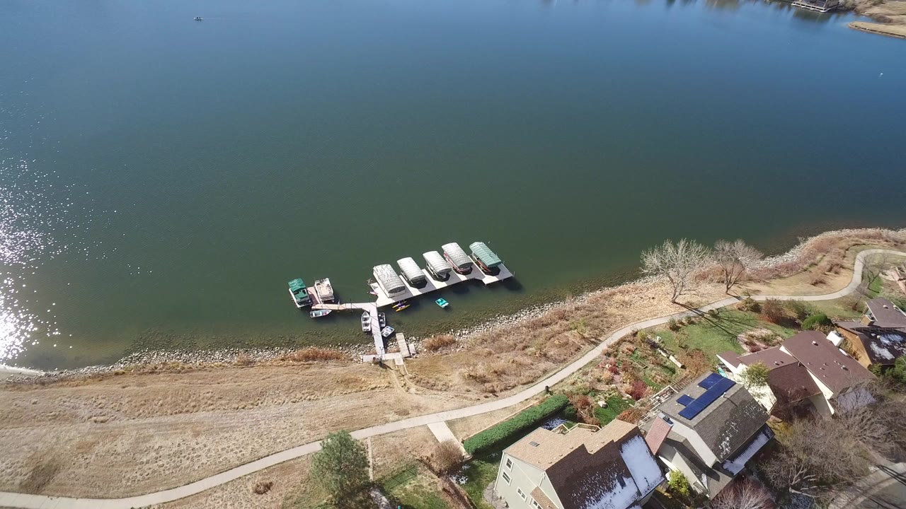 Aerial view of a lake shoreline with docks and nearby houses.