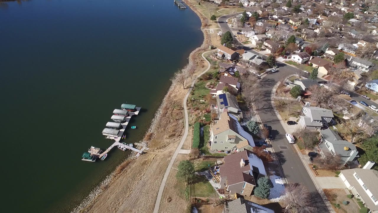 Aerial view of shoreline homes beside dark green water and boat docks.