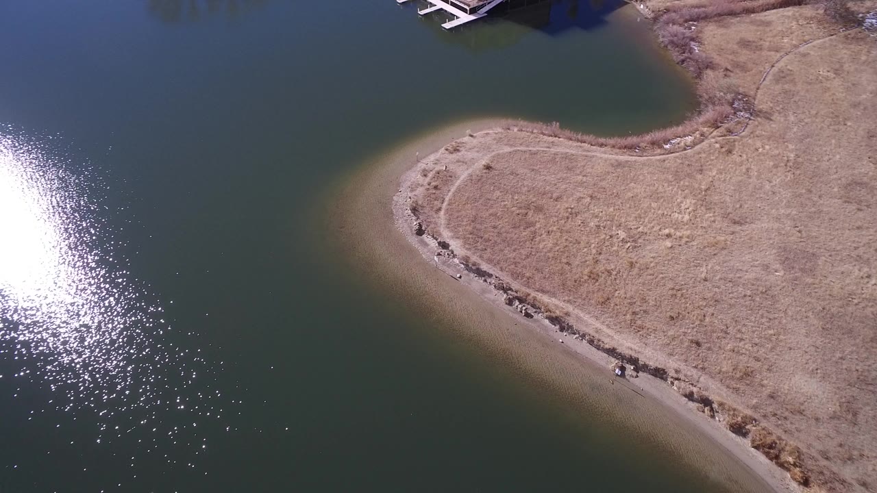 Aerial view of green water beside a dry curved shoreline.