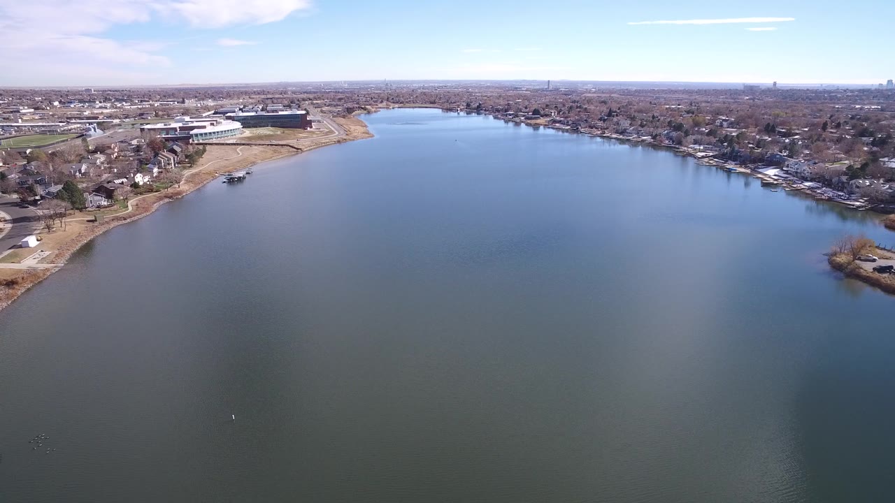 Aerial water view with curved shoreline, neighborhood streets, and distant skyline.