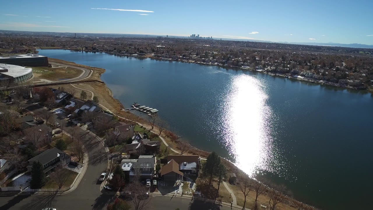 Aerial view of a lake beside suburban houses and a large modern building.