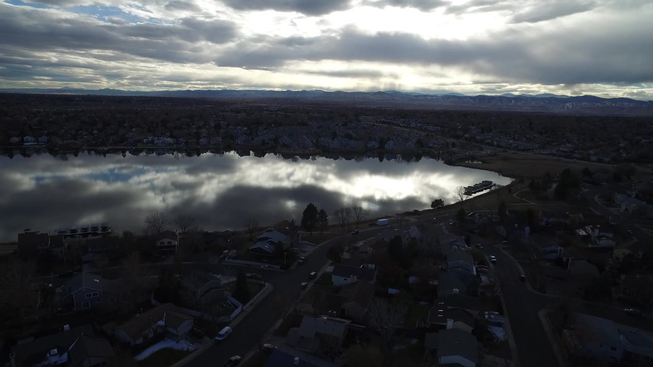 Aerial view of a suburban lake under dark evening clouds.
