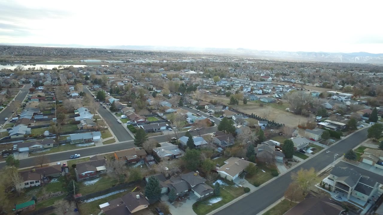 High view of homes, streets, trees, and distant landscape