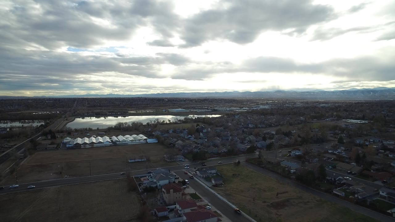 Aerial view of roads, fields, a lake, and dark clouds over a town