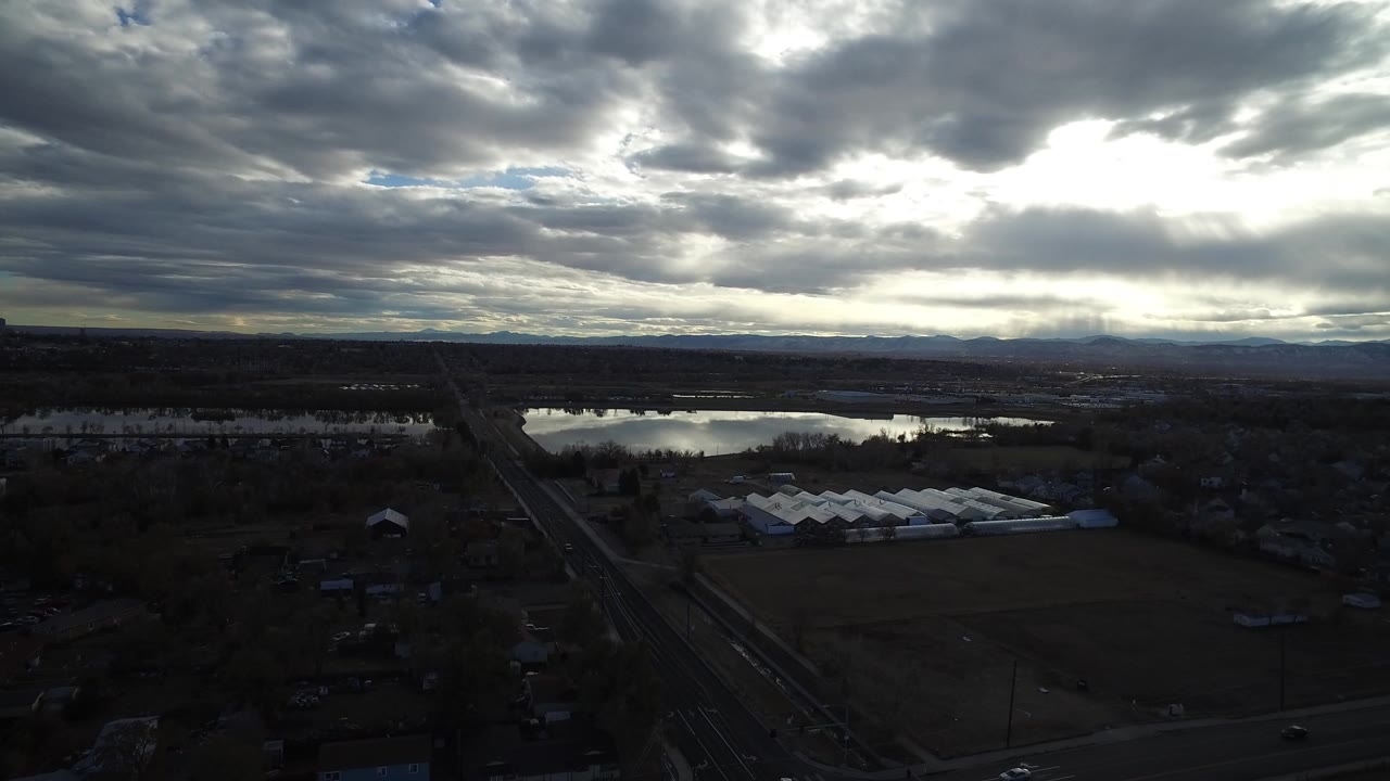 Overcast aerial landscape with water, roads, fields, and distant mountains.