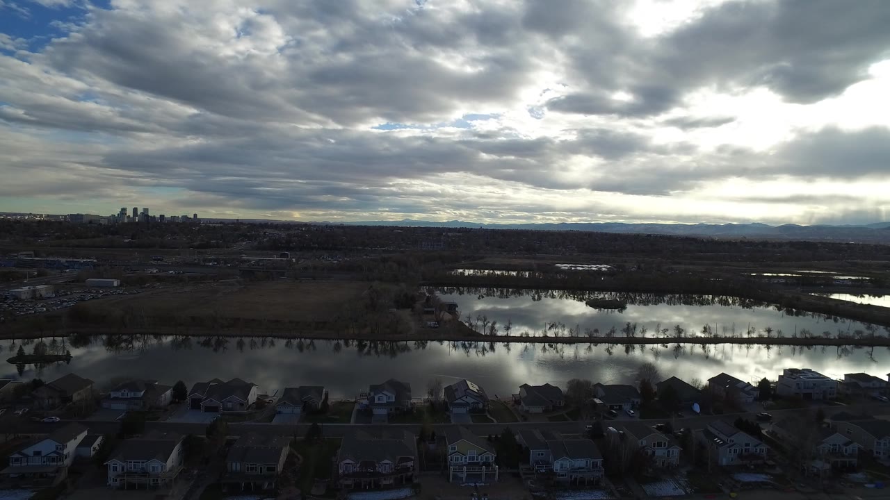 Aerial view of flooded water near suburban homes under heavy clouds.