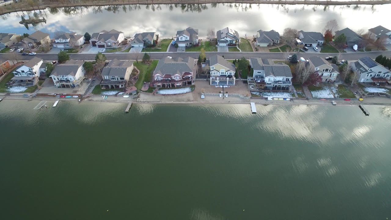 Aerial view of lakeside houses beside green water and a road.