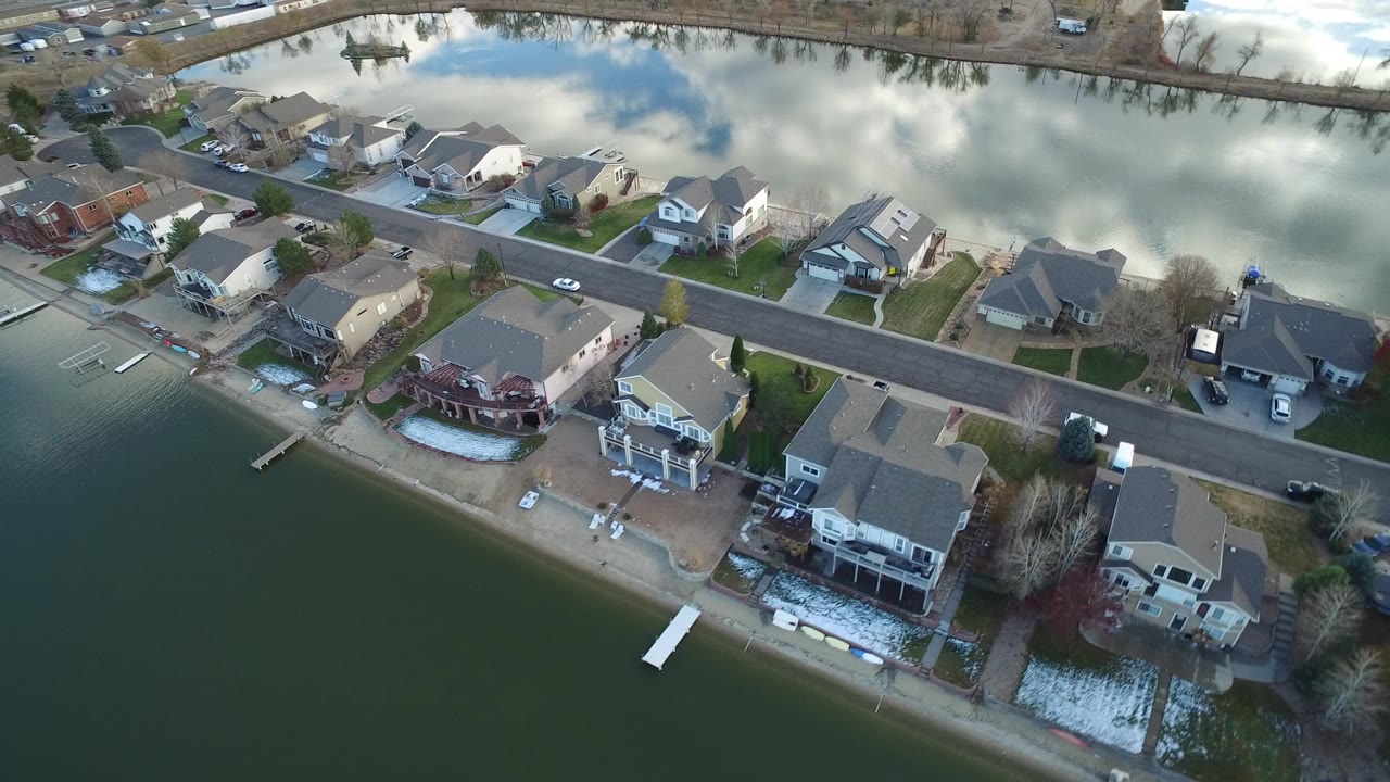 Aerial view of waterfront homes beside a paved residential road.