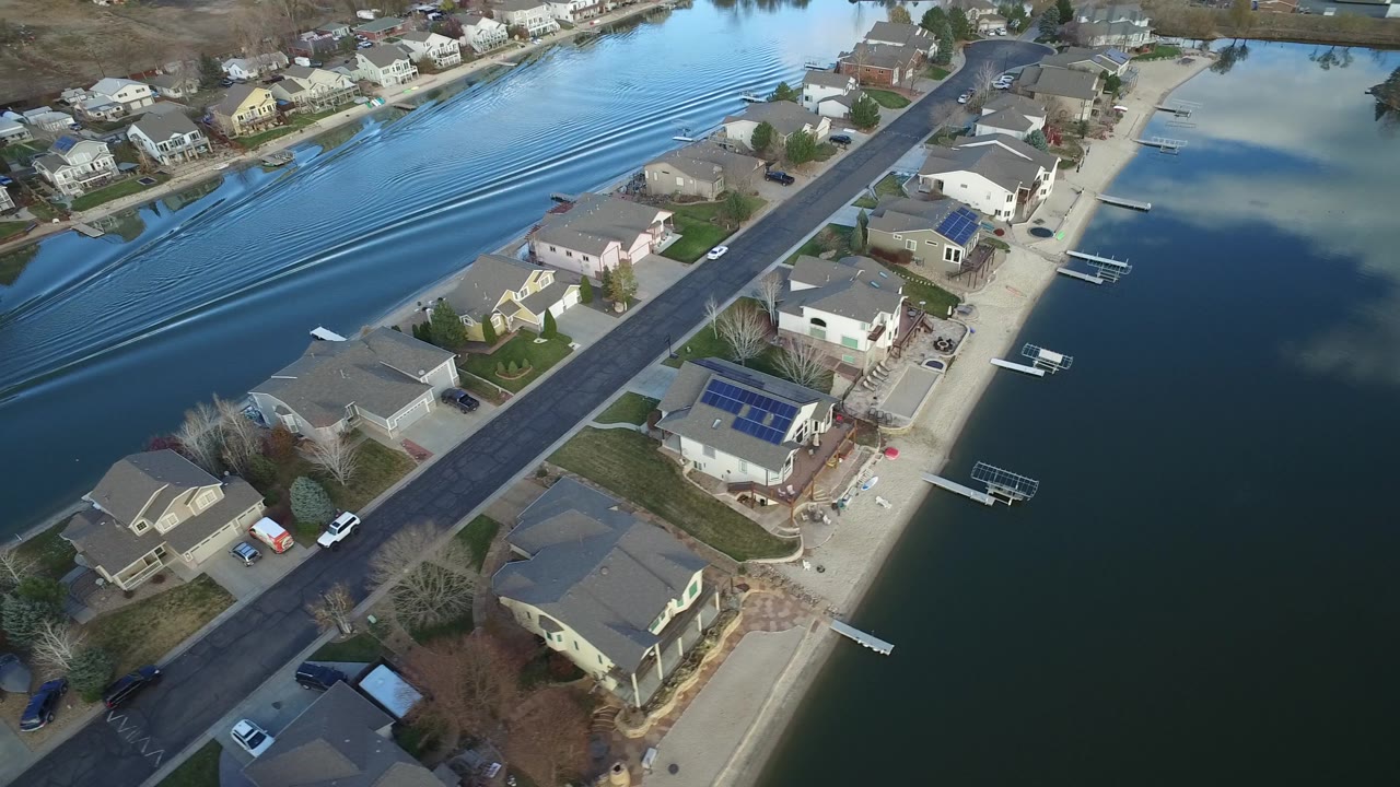 The second frame shows the Westminster residential shoreline from above, with the wake spreading across the channel and houses with docks lining both sides, with tiny people visible near the shore.