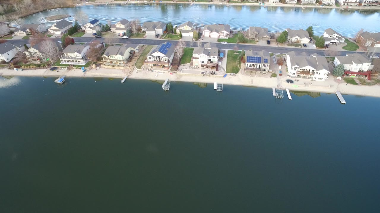 Aerial view of waterfront houses, docks, and dark water.