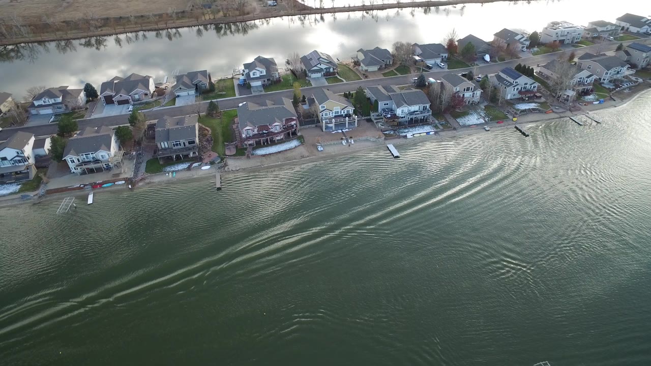 Aerial view of waterfront houses and rippled green water.