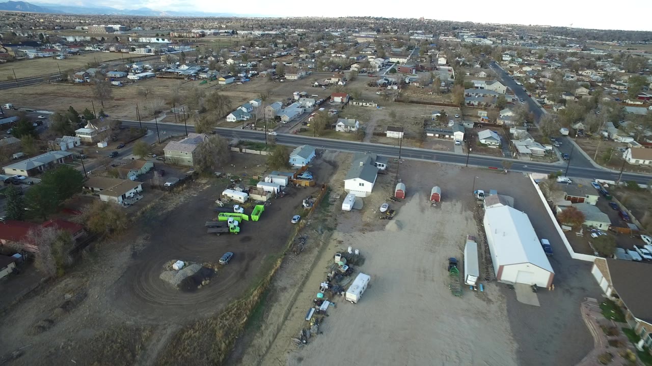 Aerial view of a road, homes, open lots, and industrial yards.