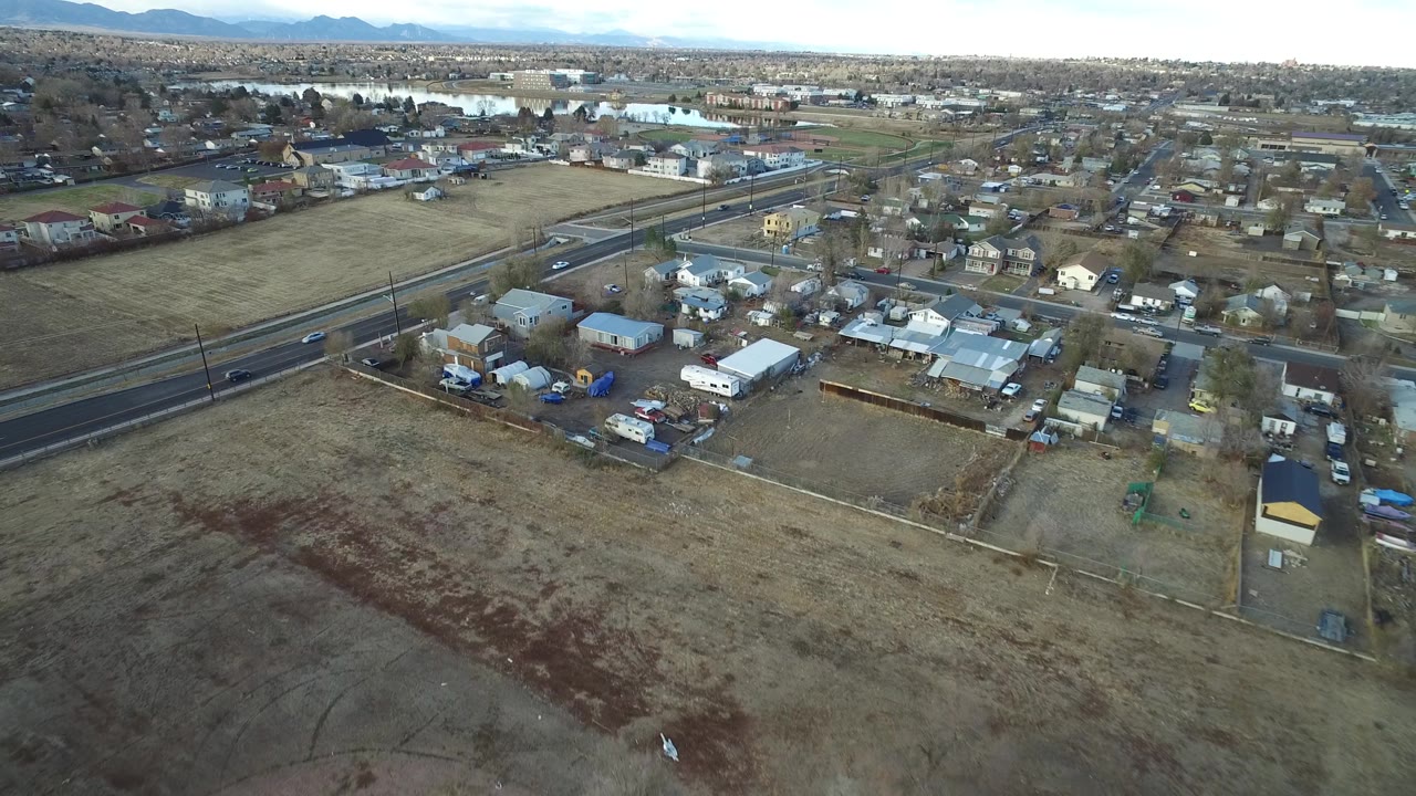 High aerial view of roadway, homes, and open brown field.