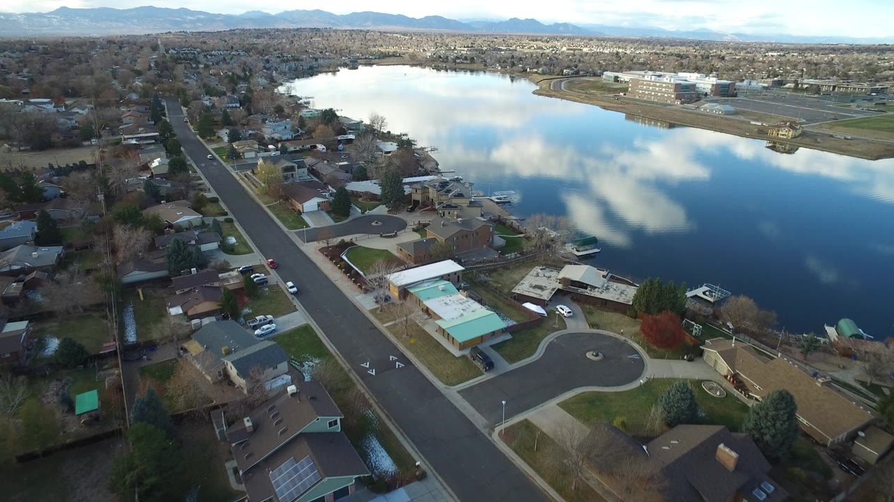 Aerial view of houses beside a large lake with mountains in the distance.
