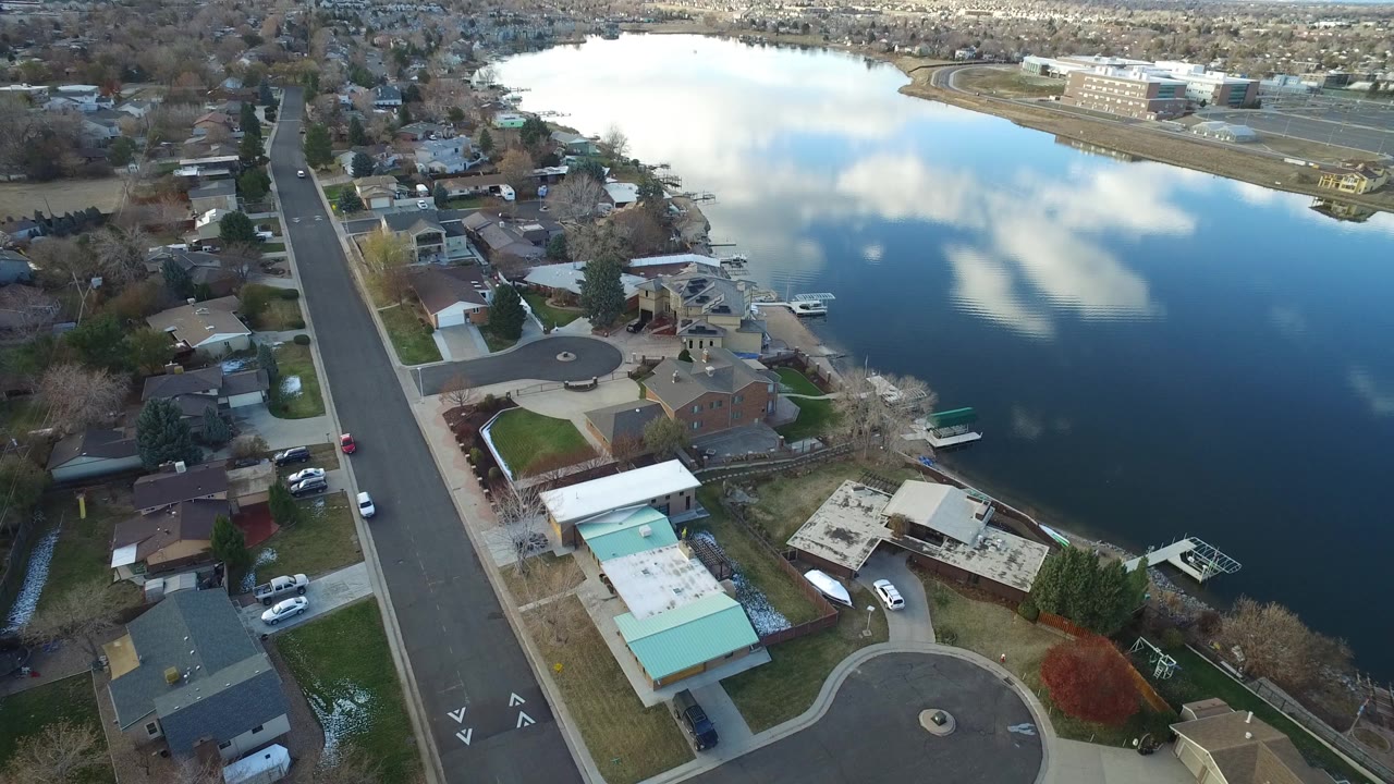 Aerial view of homes, a residential street, and a lake.