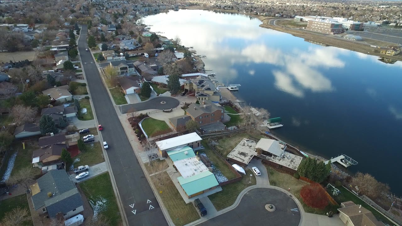 Aerial view in Westminster, Colorado looking across private homes, small docks, and bright cloud reflections on the lake, with no visible people.