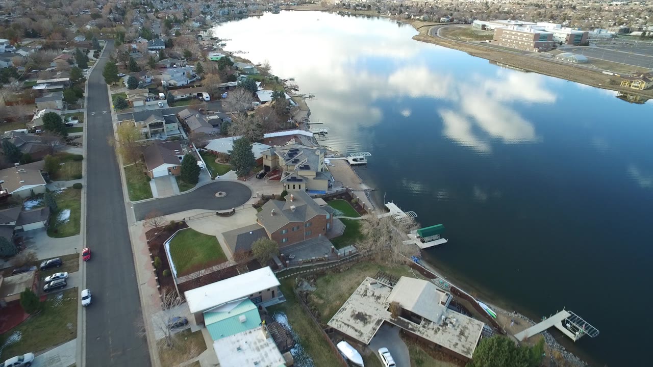 Aerial neighborhood view with lake, road, and waterfront homes