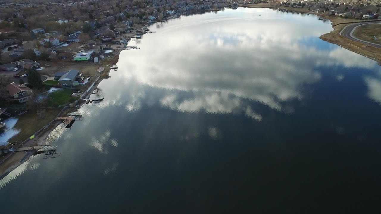 Aerial view of a reflective lake bordered by homes and docks.