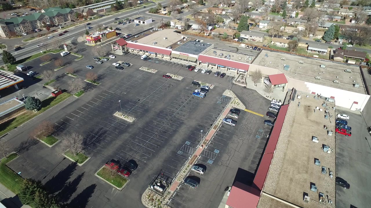 Aerial view of a mostly empty parking lot beside commercial buildings.