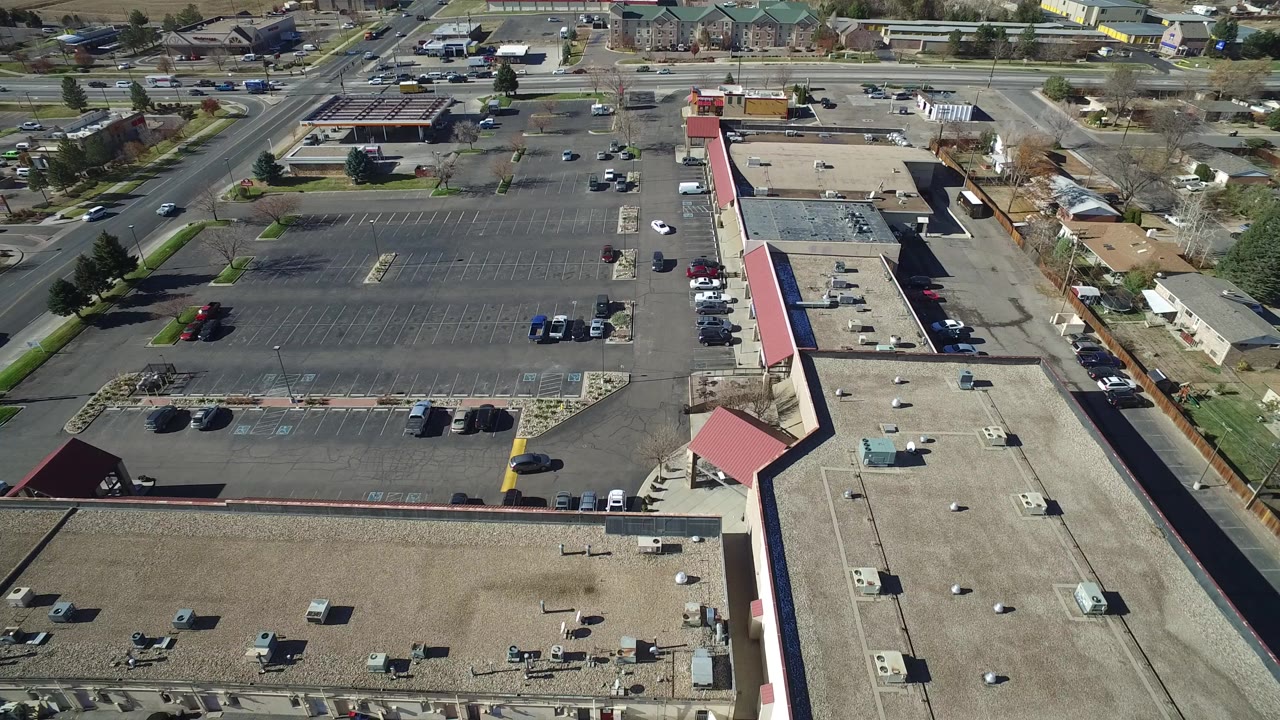 Aerial view of a commercial building beside a large parking lot and roads.