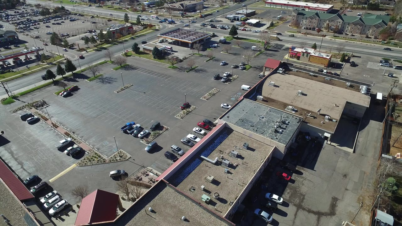 Aerial view of commercial buildings and a large parking lot beside a road.