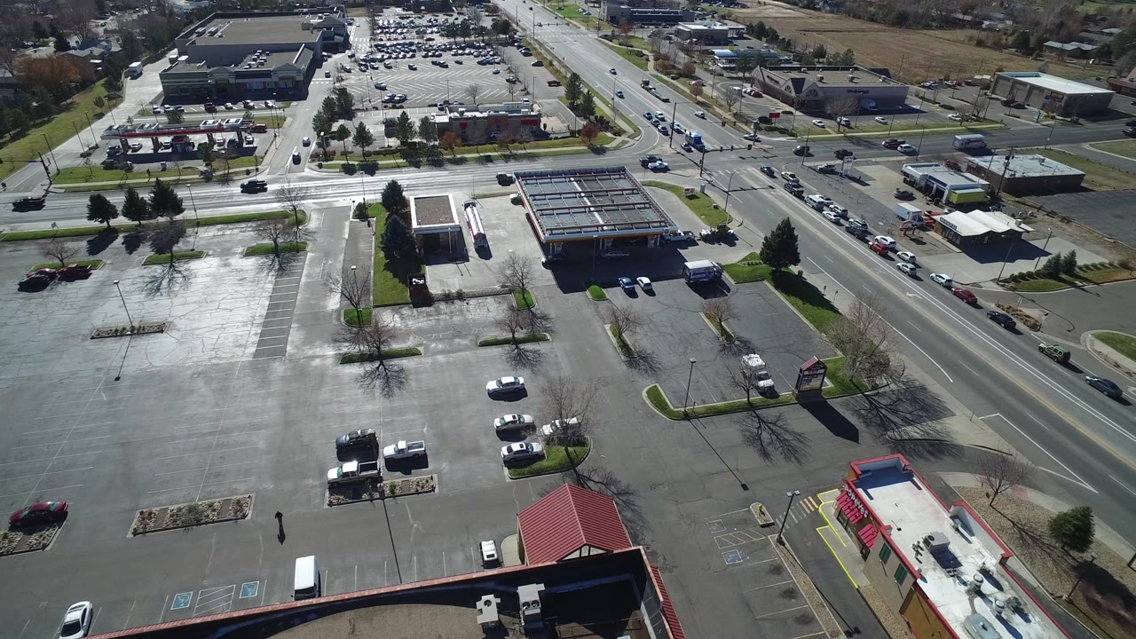 High angle aerial over a busy road and parking lots.