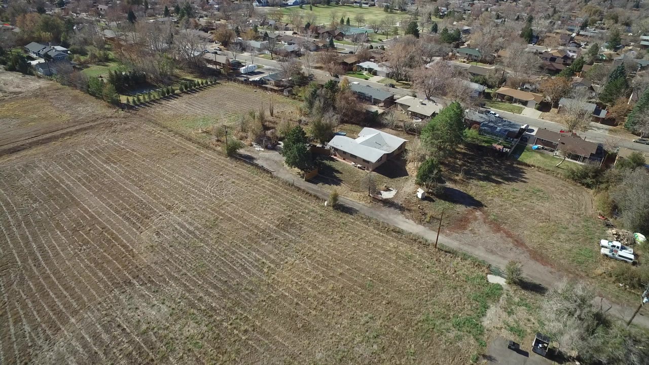 Aerial view of a plowed field beside suburban homes and trees.