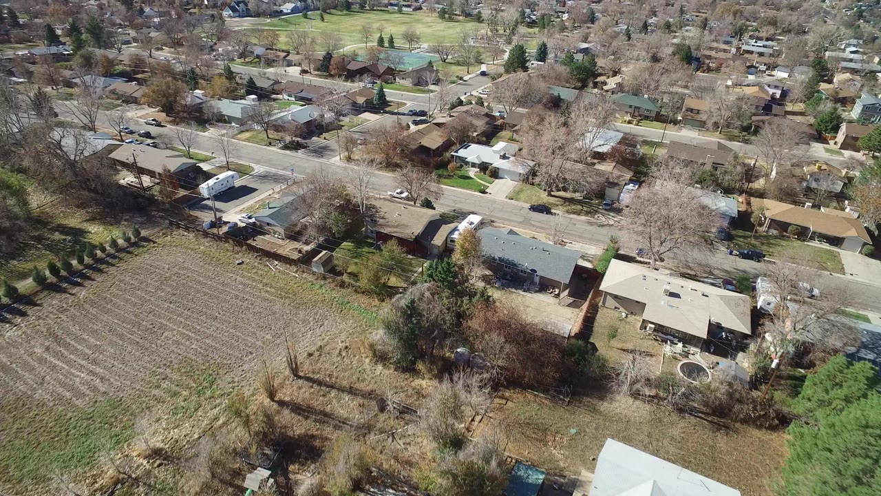 Aerial view of houses beside a tilled field and residential streets.