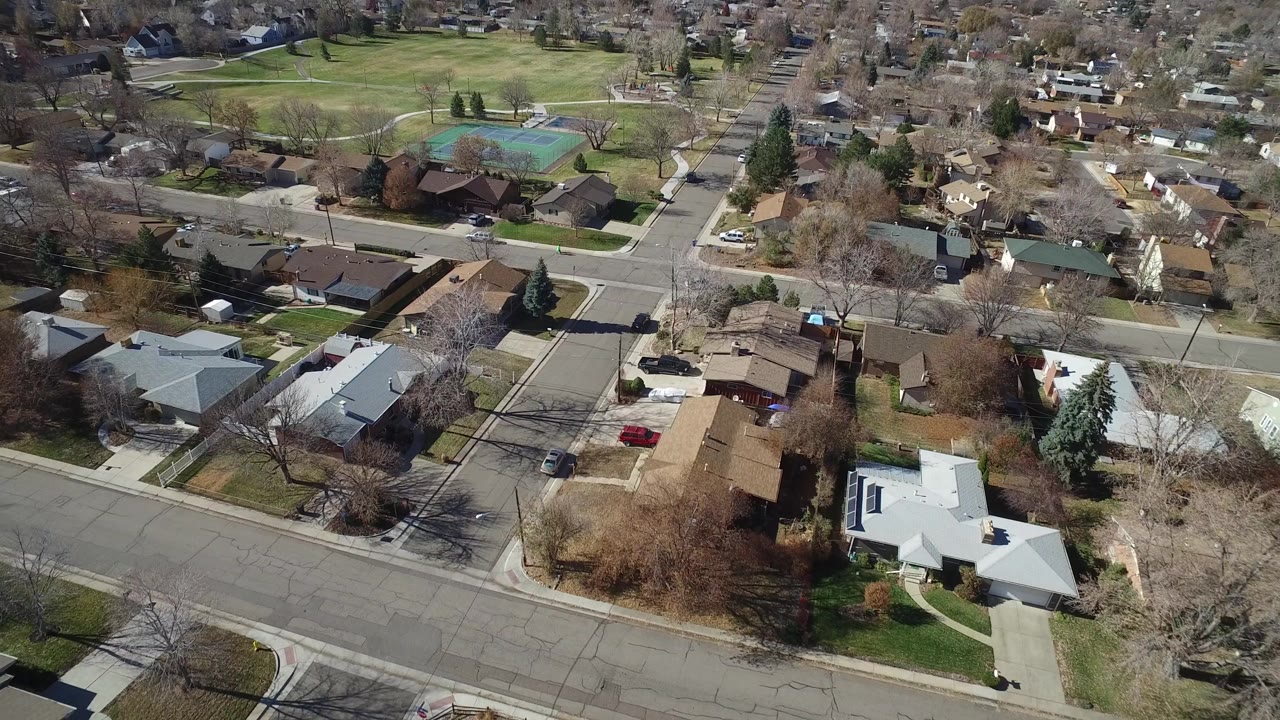 Aerial view of suburban houses, streets, trees, and tennis courts.