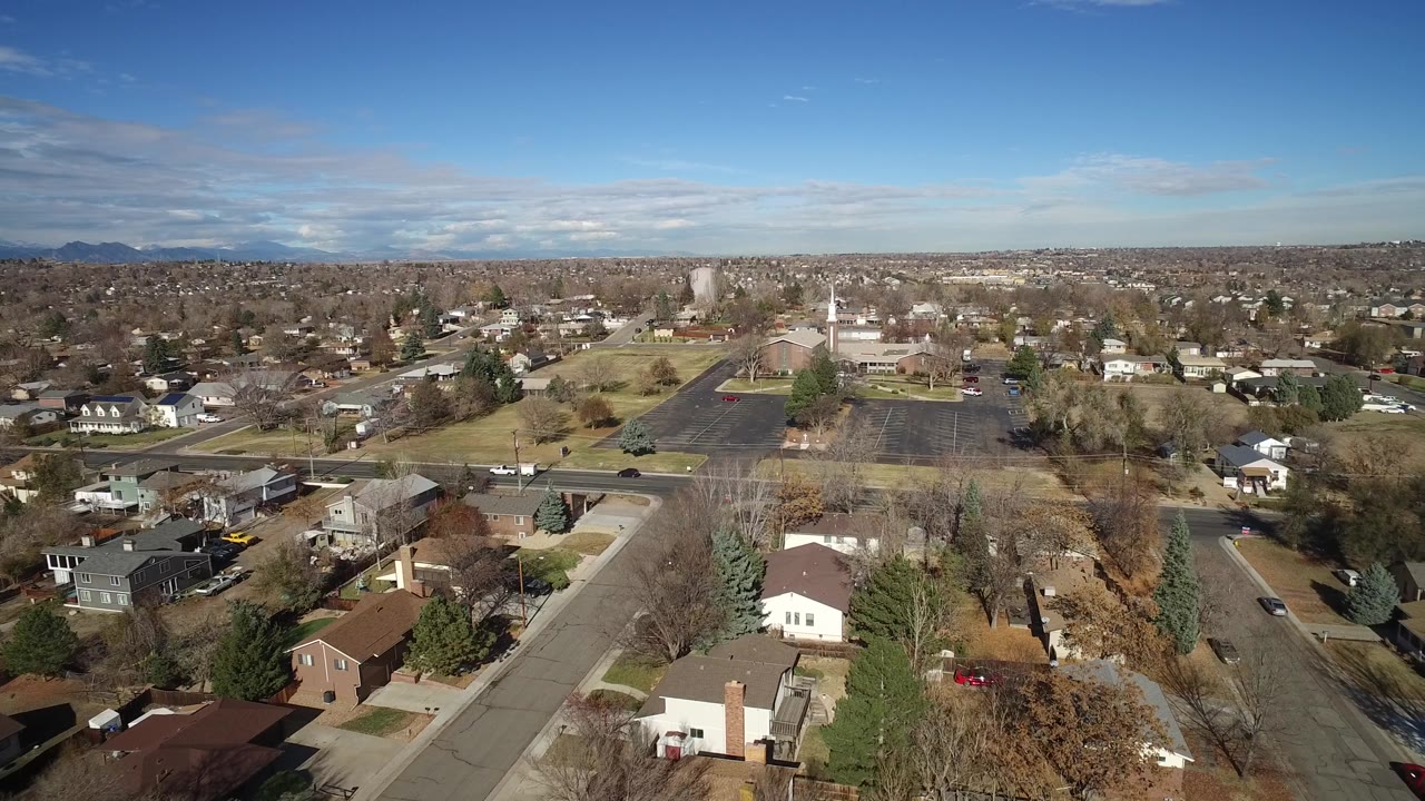 Aerial neighborhood view with homes, streets, and parking lot