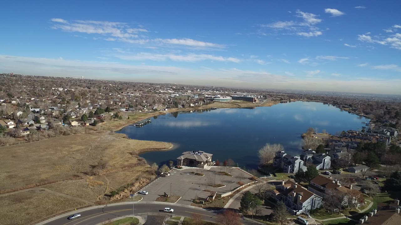 Aerial view of a lake bordered by suburban homes and dry grass