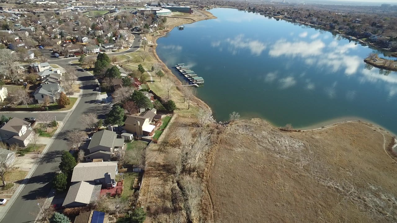 Aerial view of a suburban lake, houses, roads, docks, and dry shoreline grass.