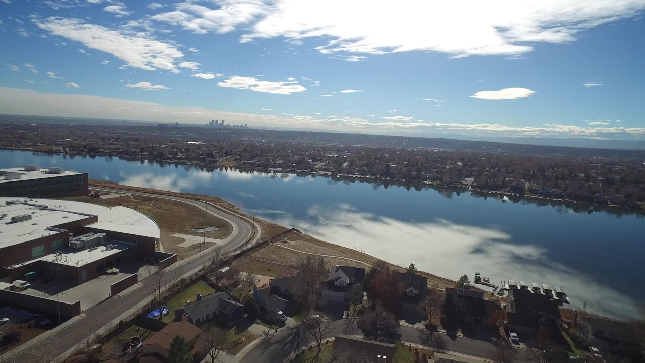 Aerial view of a reflective lake beside buildings and roads.