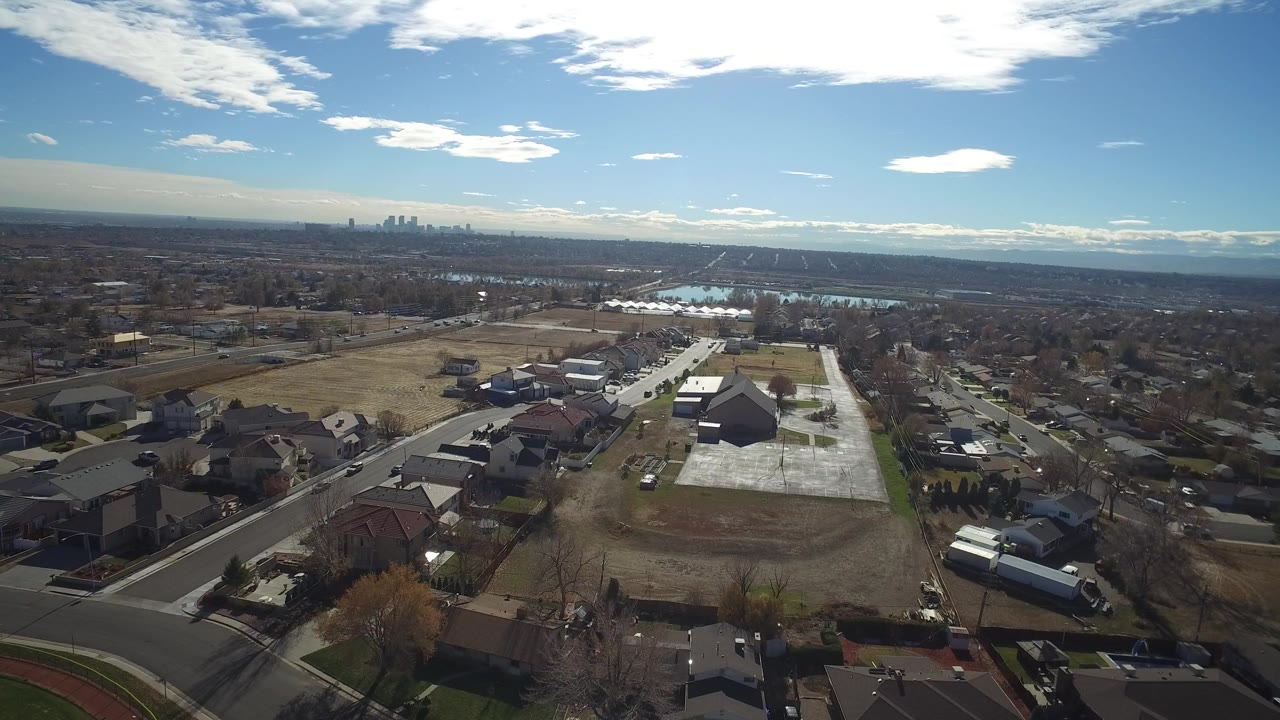 Aerial view over suburban houses and streets under a bright sky.