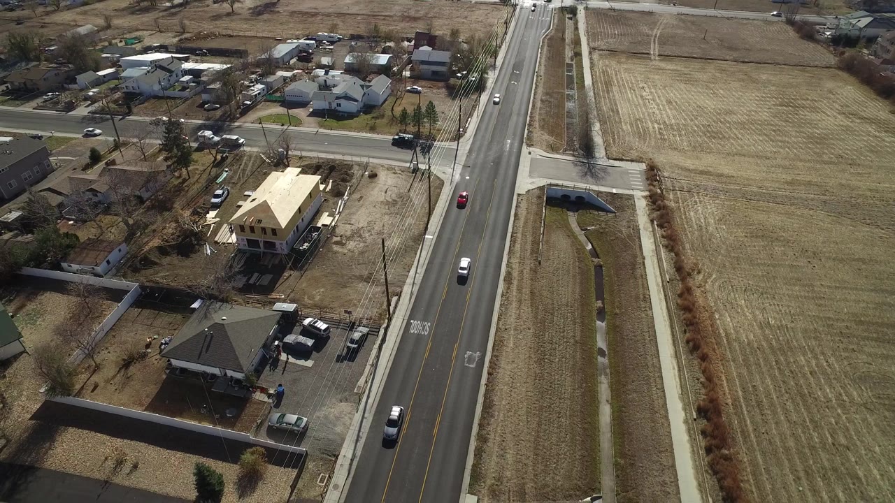 Aerial view looking down on houses, road traffic, and a large field.