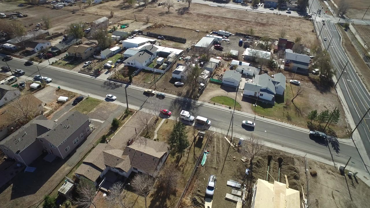 Aerial view of homes beside a paved residential street with cars.