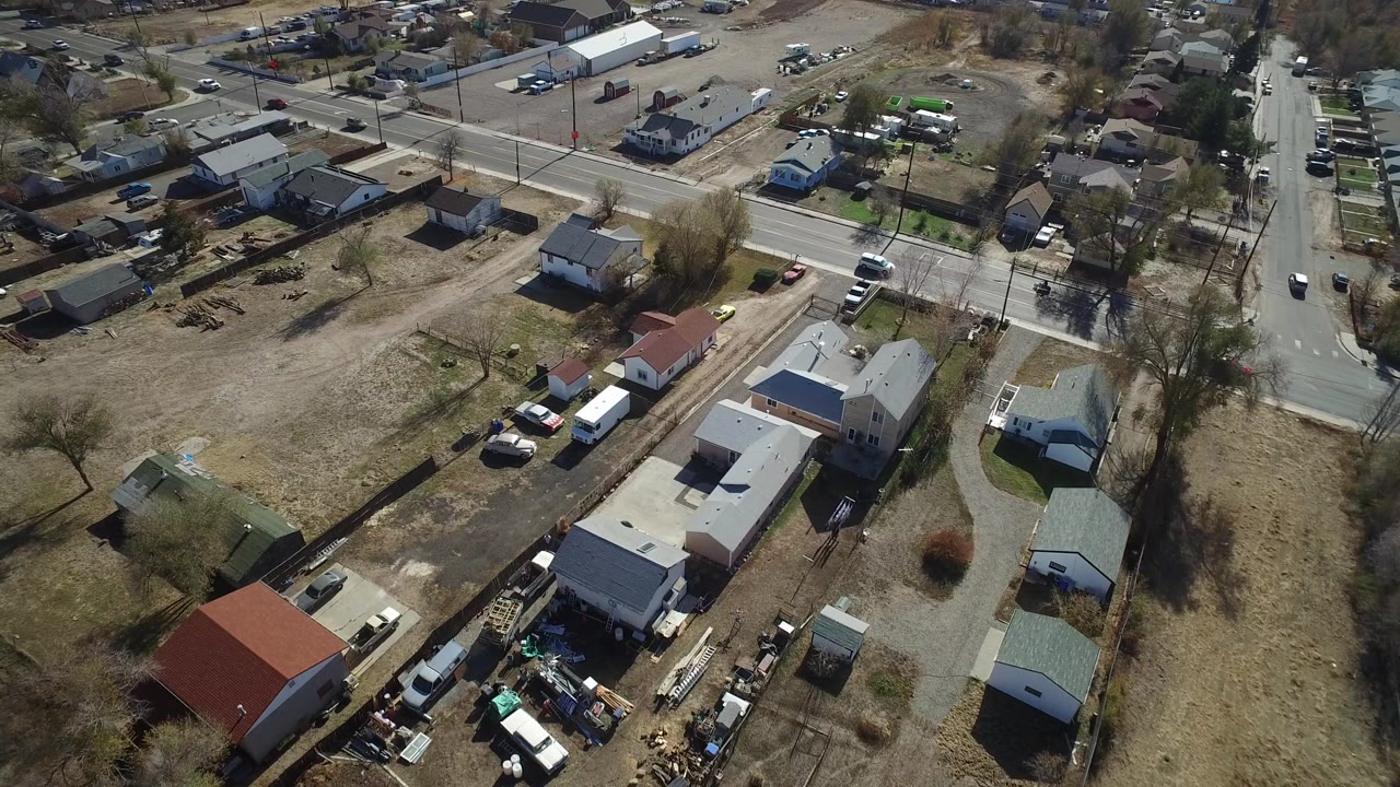 Aerial view of a road, houses, open lots, and parked vehicles