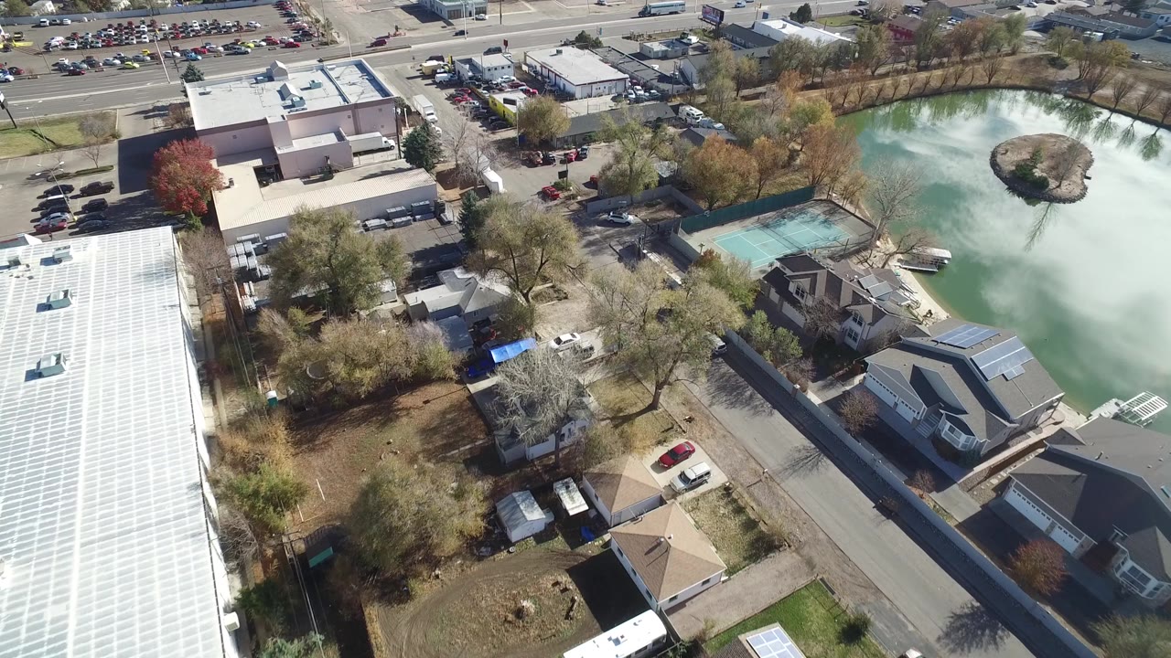 Westminster, Colorado aerial frame with the pond on the right, tennis courts near the lower center, houses, trees, parked cars, and no visible people.