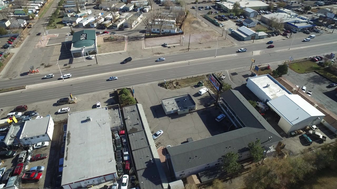 Aerial view of cars on a multi-lane road beside low industrial buildings.